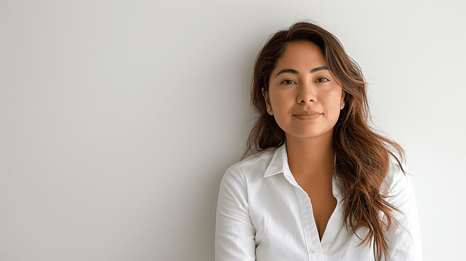 A woman looking straight into the camera against a plain wall